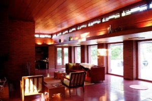 A living room is filled with warm light shining in from it's floor to ceiling windows. 